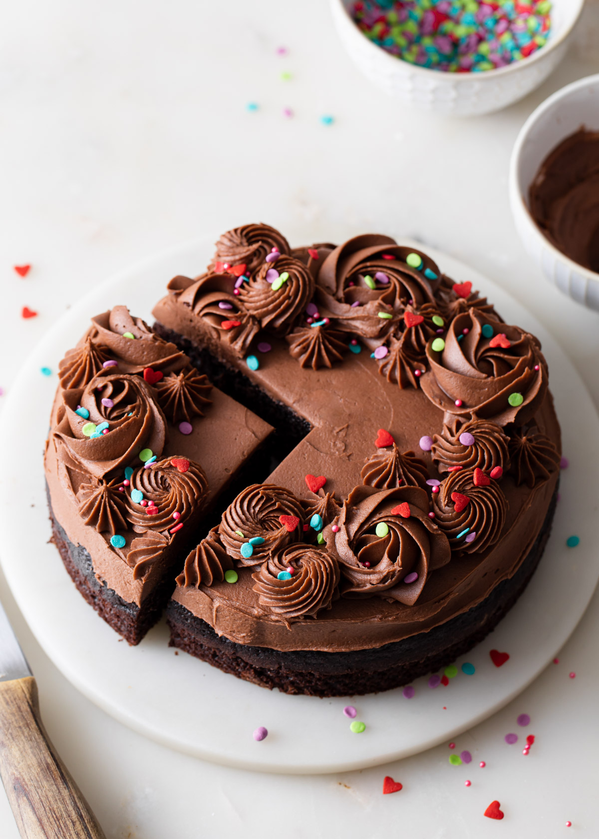 A mini chocolate cake for two with fudge frosting and sprinkles that's been sliced