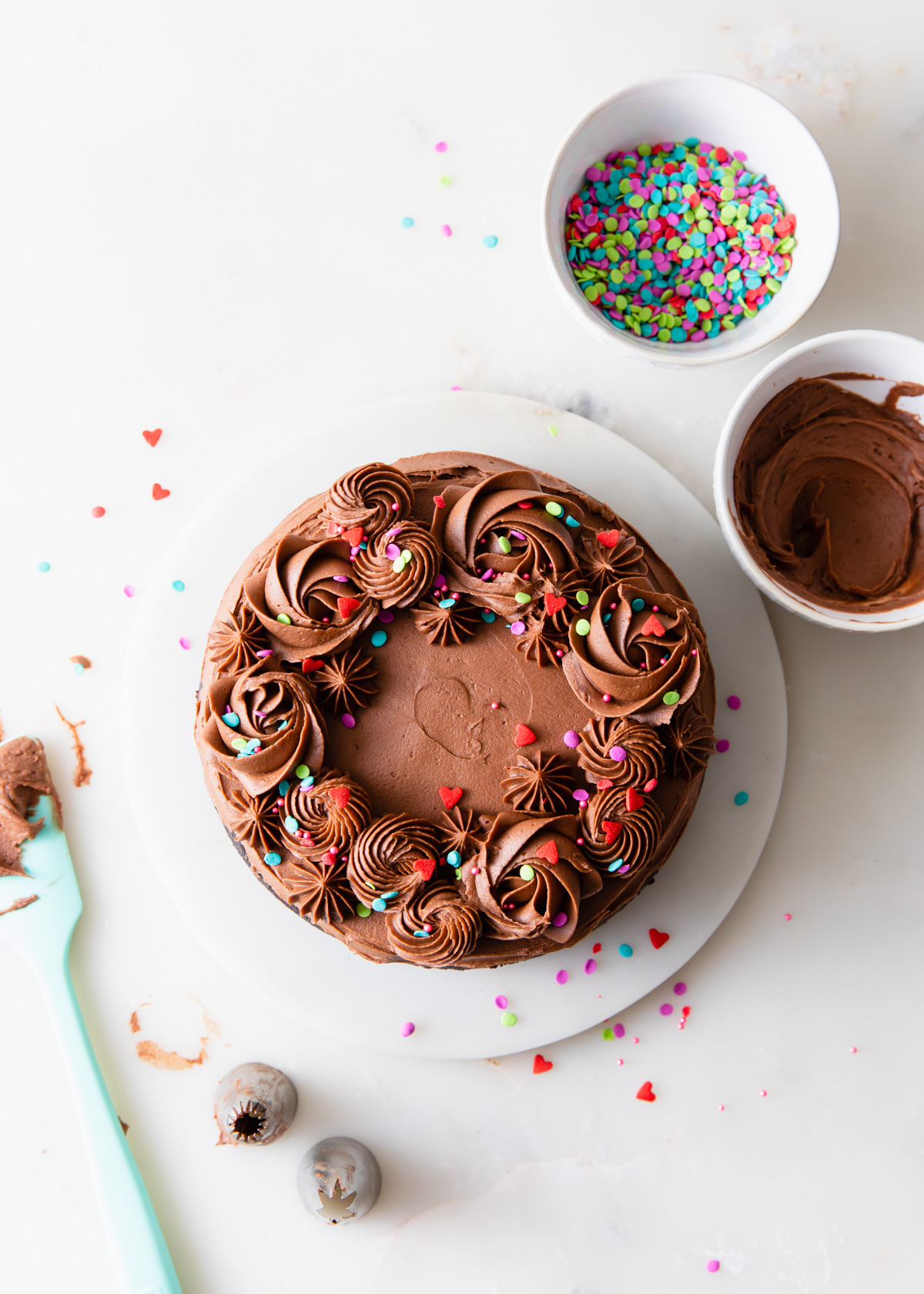 An overhead image of a mini chocolate cake for two with fudge frosting and sprinkles