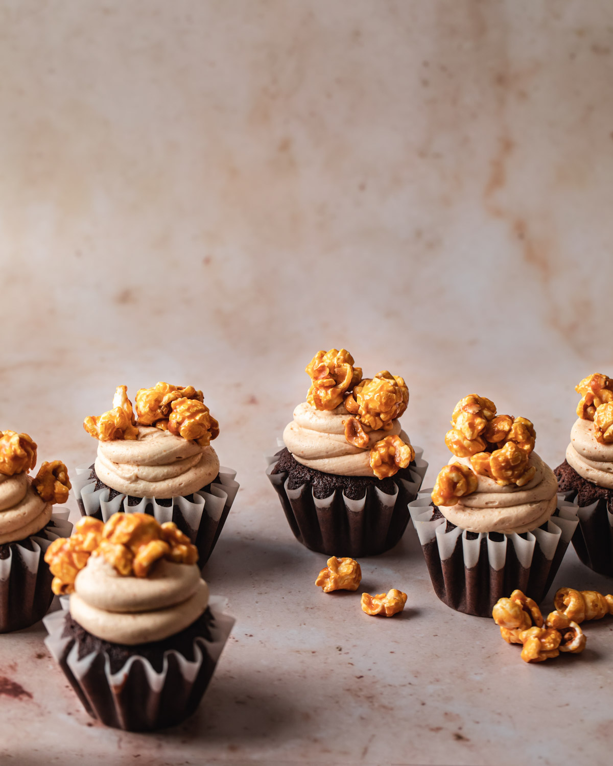 Chocolate cupcakes with swirls of peanut butter frosting on top a caramel popcorn