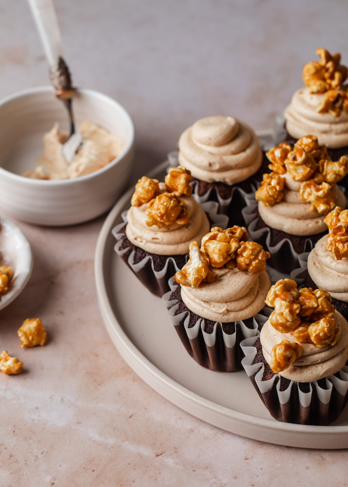 A platter of chocolate peanut butter cupcakes with caramel corn on top.
