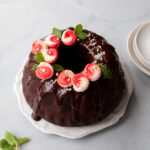 A chocolate bundt cake with ganache glaze and piped peppermint buttercream on top