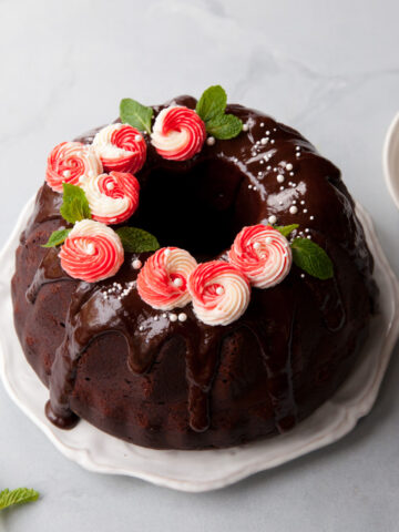 A chocolate bundt cake with ganache glaze and piped peppermint buttercream on top