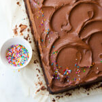A chocolate sheet cake with swirls of fudge frosting and sprinkles