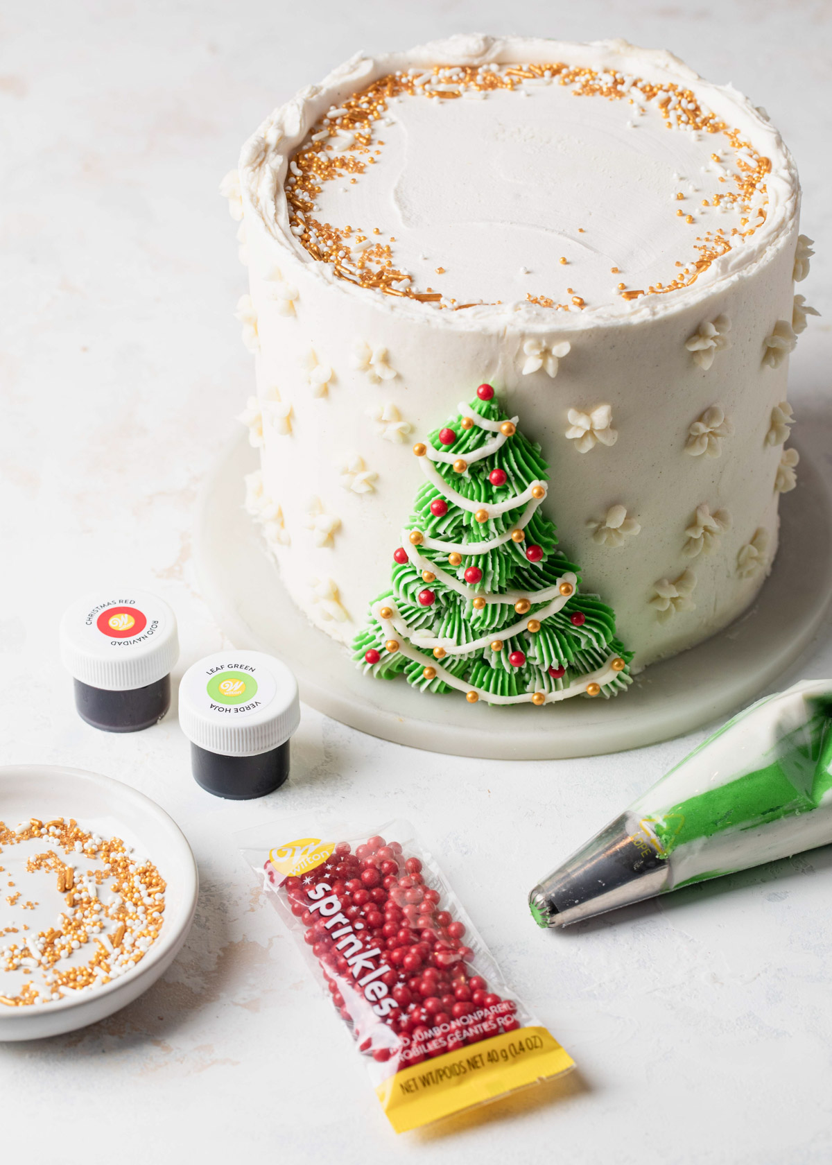A white cake with a green buttercream Christmas tree piped on the front