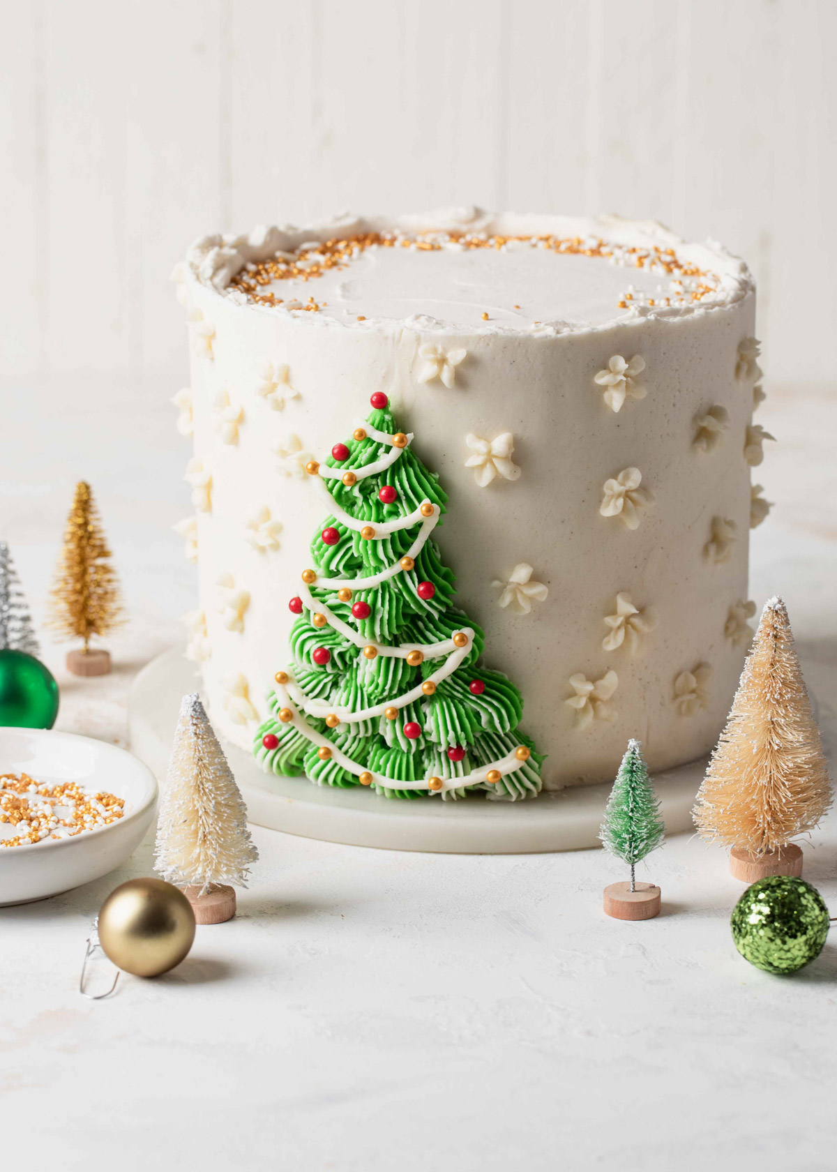 A white cake with a green buttercream Christmas tree piped on the front