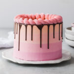 A pink, orange, and purple stripe vanilla cake with chocolate drip