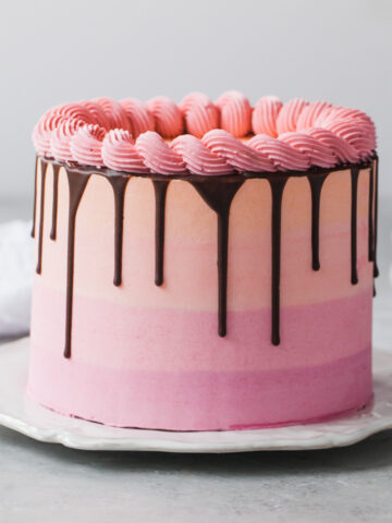 A pink, orange, and purple stripe vanilla cake with chocolate drip