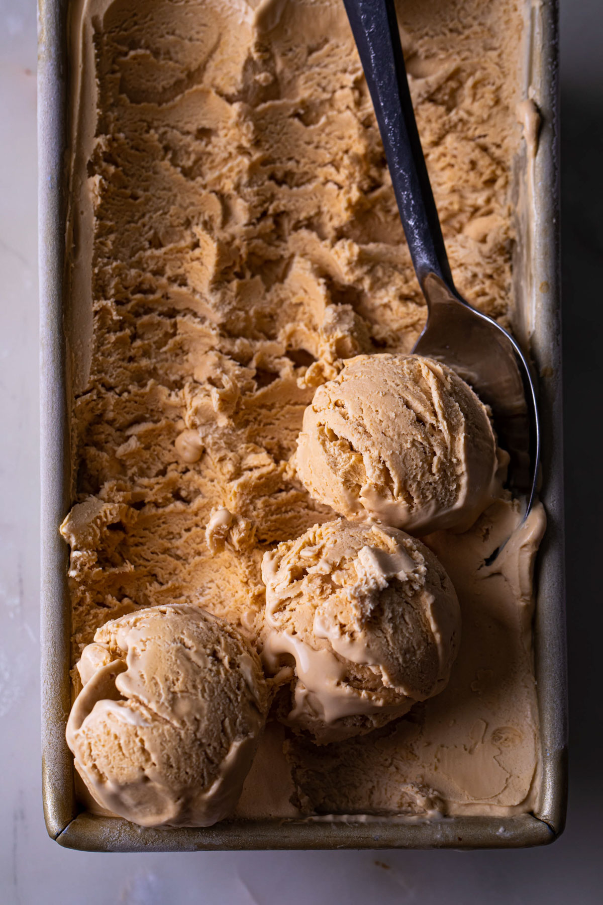 Scoops of creamy dulce de Leche no churn ice cream in a loaf pan
