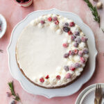 A no-bake eggnog cheesecake with piped whipped cream and sugared cranberries on top