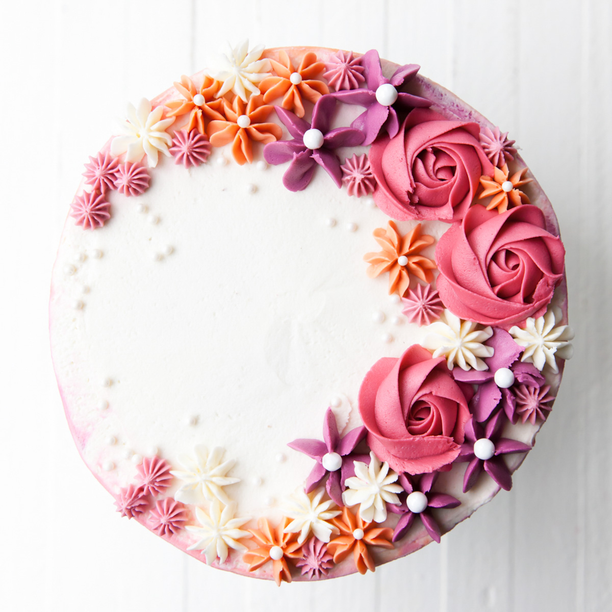 An overhear image of a cake with piped buttercream rose on top