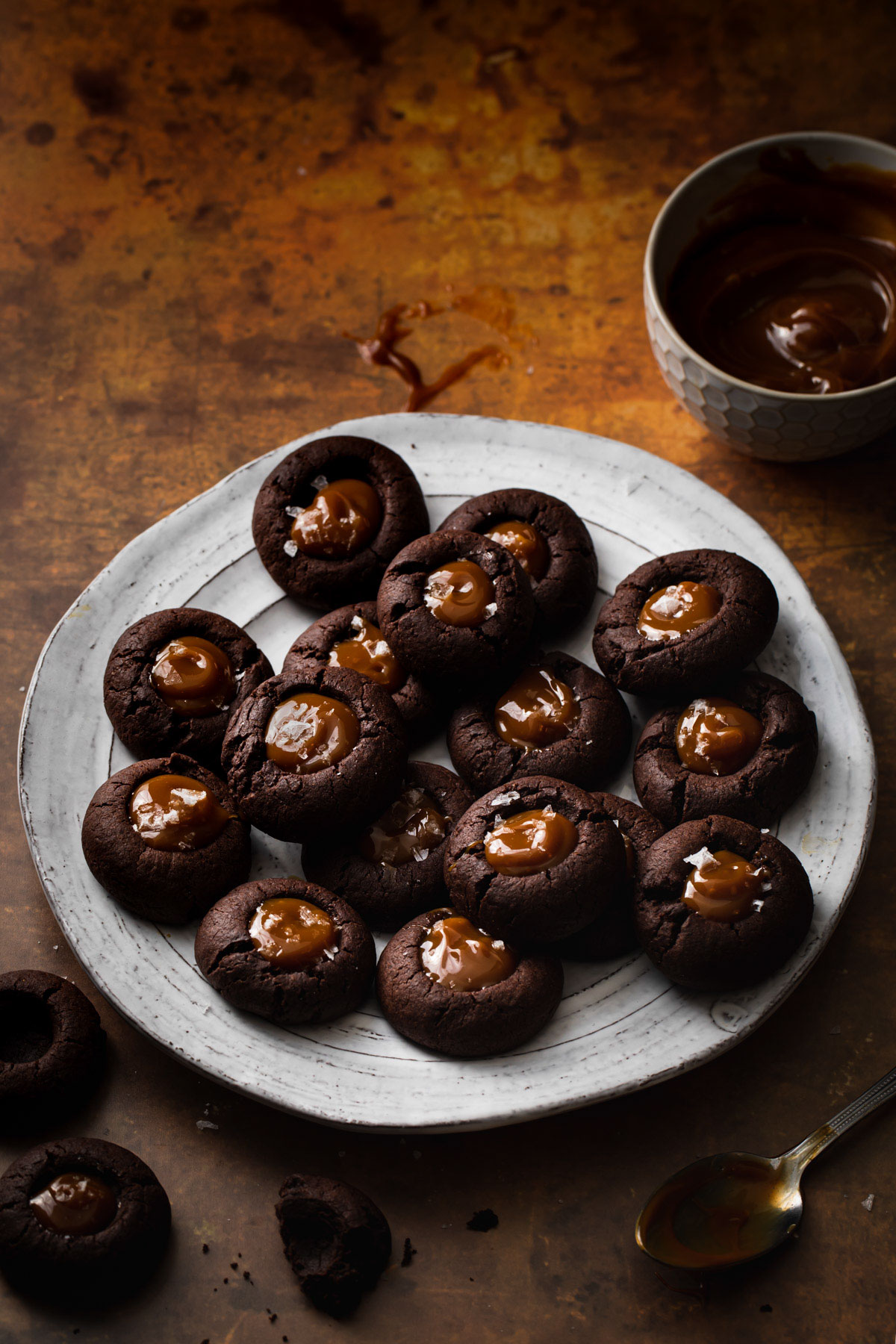A plate of chocolate gingerbread thumbnail cookies with dulce de leche centers set on a gold backdrop
