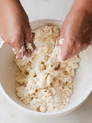 A bowl of pie dough being made by hand