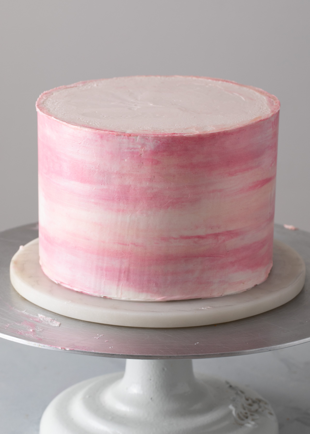 A pink buttercream watercolor cake with smooth icing