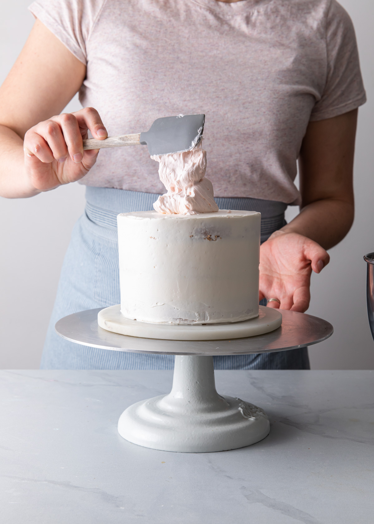 Adding buttercream to the top of a cake to create a watercolor finish