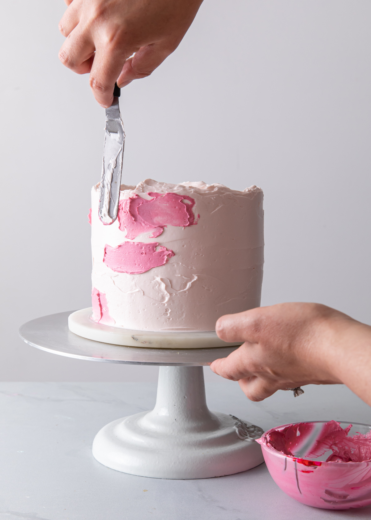 Adding pink buttercream to a watercolor cake