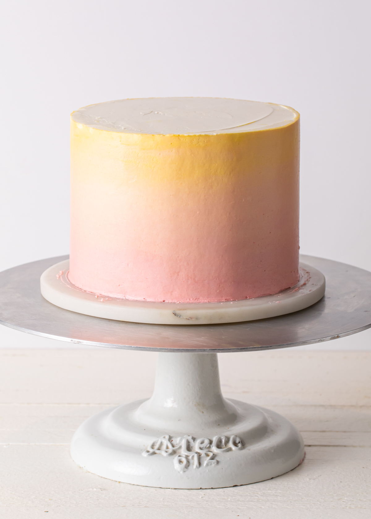 A pink ombre cake on a rotating cake stand.