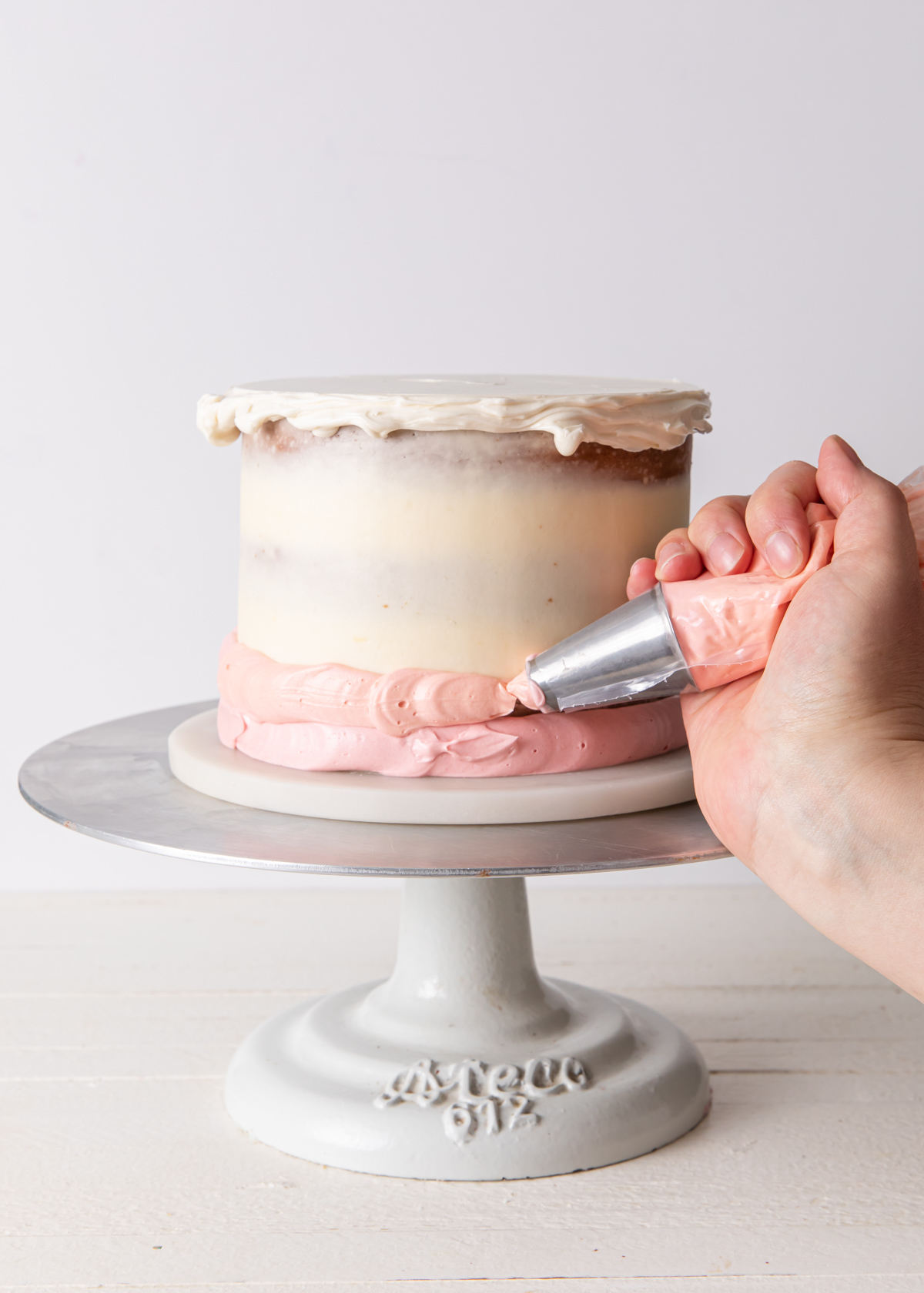 Buttercream being piped on the sides of cake