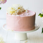 A pink lemon poppy seed cake with raspberry jam filling and fresh flowers on top