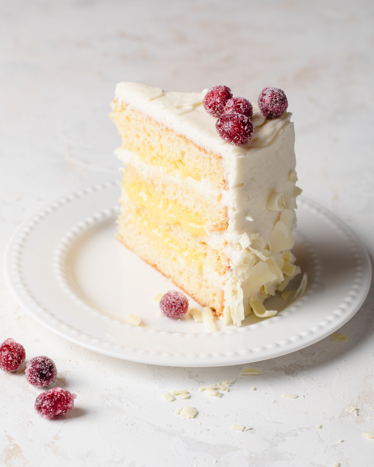 A slice of lemon layer cake with white chocolate curls on the outside