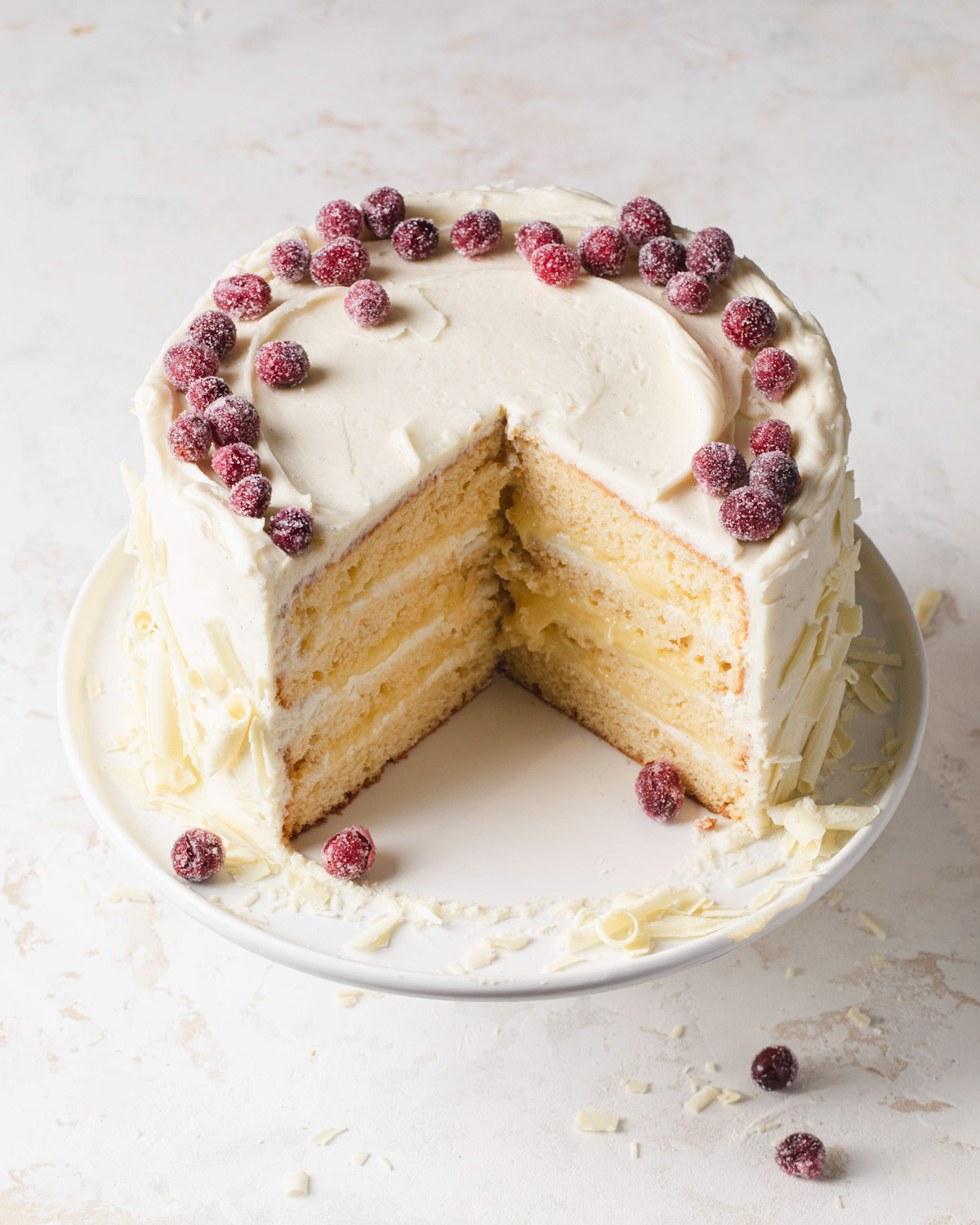 Lemon layer cake with lemon curd and white chocolate cream cheese frosting and sugar cranberries on top