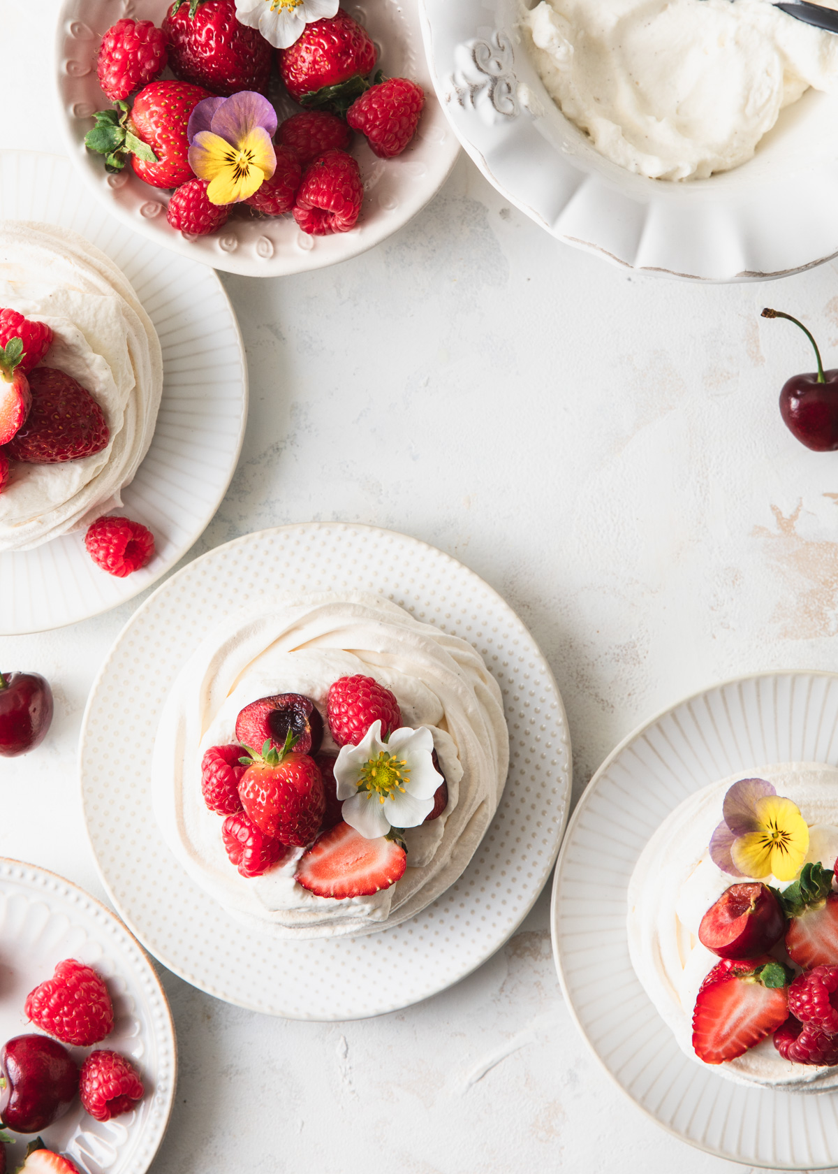 An overhead image of mini pavlovas with berries on top and edible flowers
