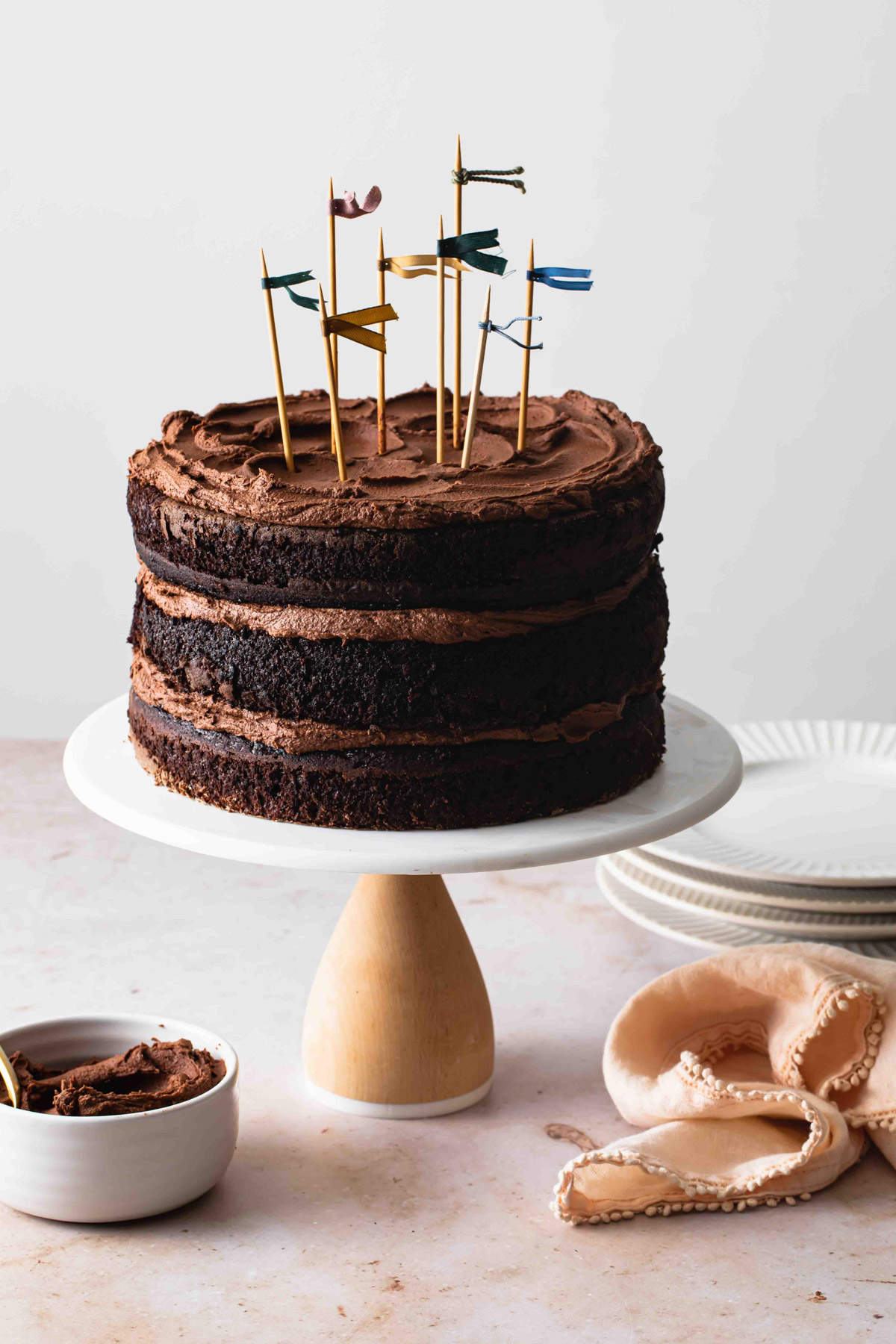 A three-layer moist chocolate cake on a cake pedestal with fudge frosting.