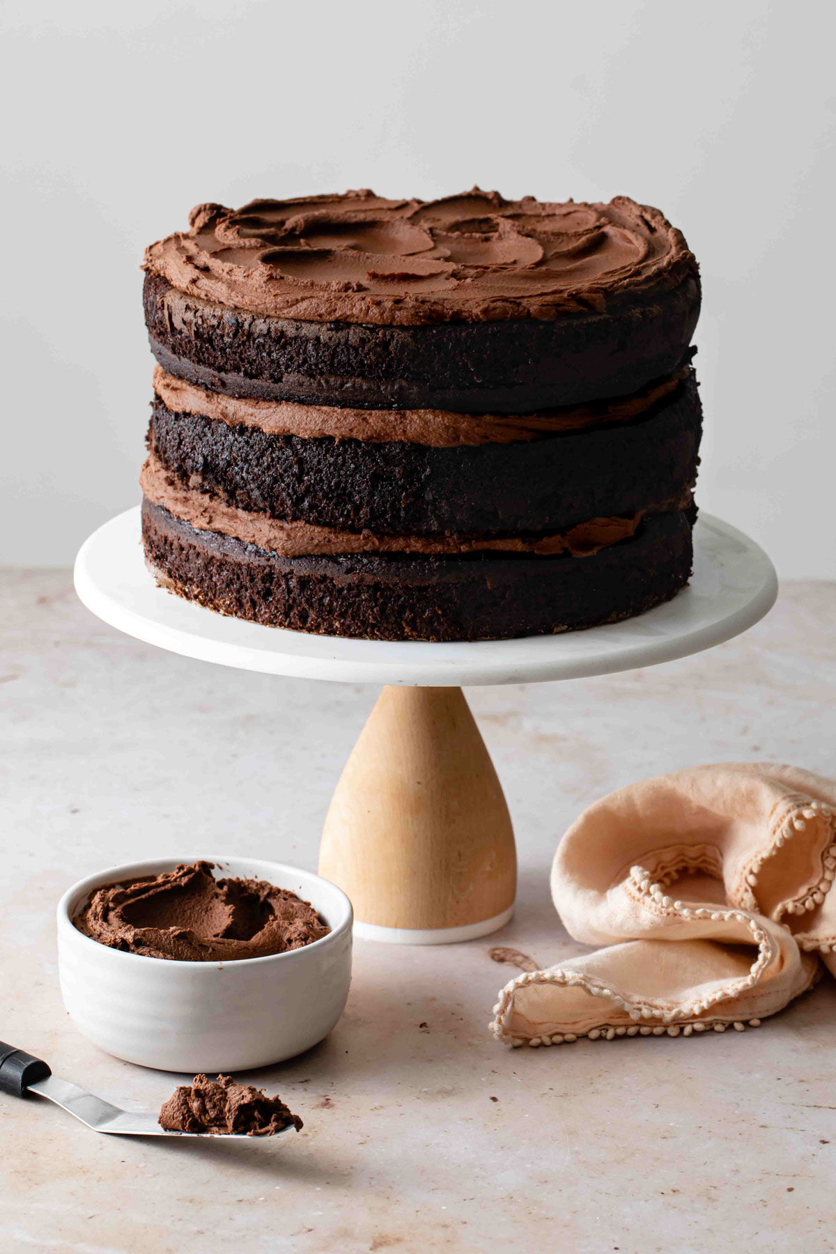 A naked three-layer chocolate cake with fudge frosting