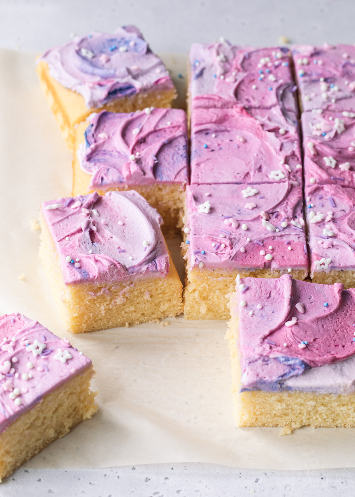 Square slices of vanilla sheet cake with swirly purple buttercream
