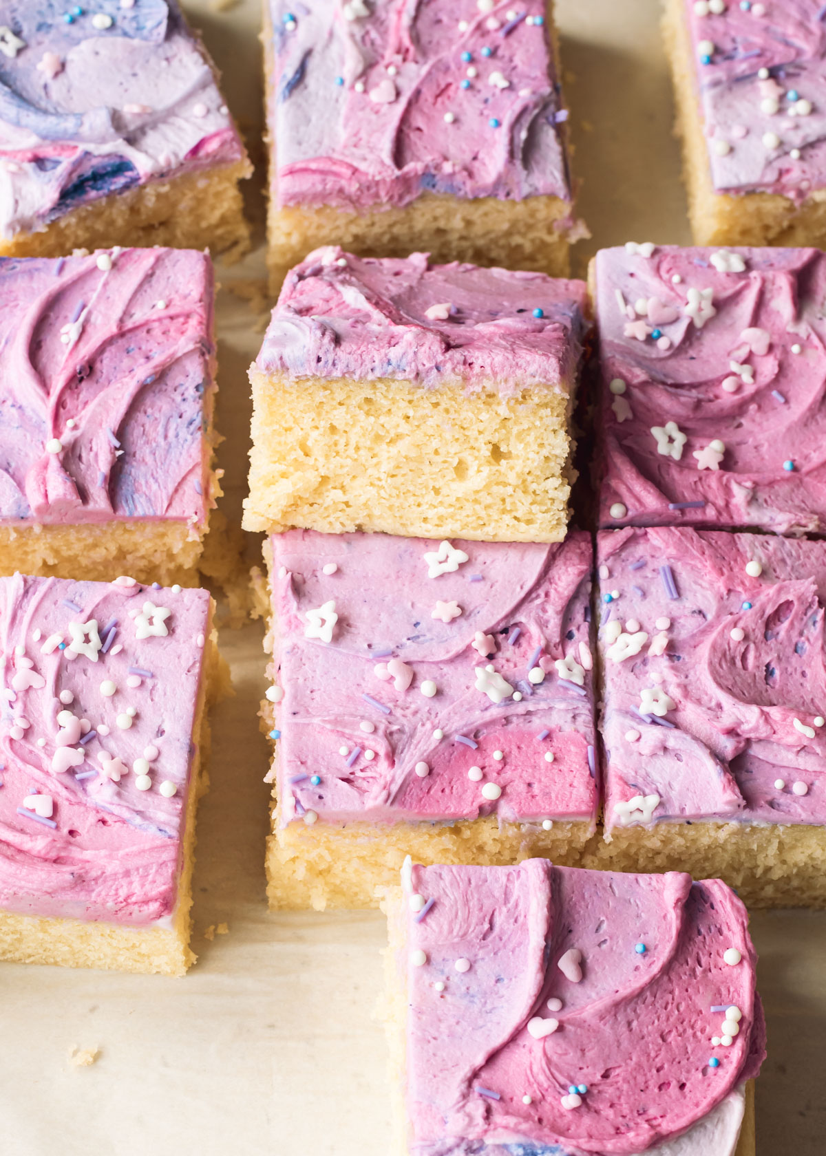 Square slices of vanilla sheet cake with swirly purple buttercream