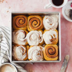 A tray of pumpkin cinnamon rolls with cream cheese frosting