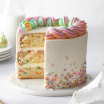 A three-layer sprinkle cake with vanilla buttercream and rainbow buttercream piped border