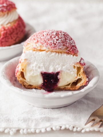 A choux bun filling vanilla pastry cream and raspberry jam