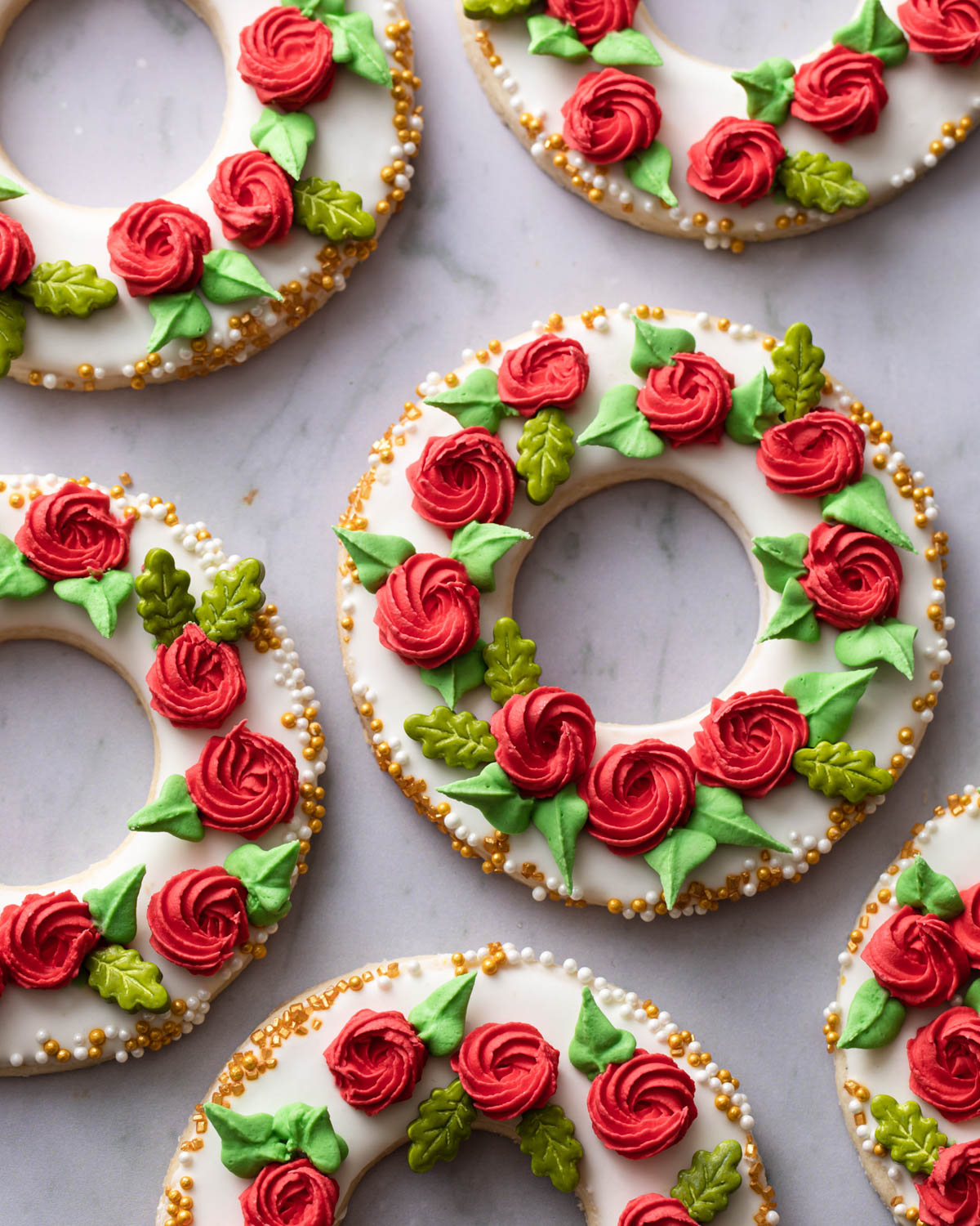 A close-up image of wreath sugar cookies with piped red rosettes