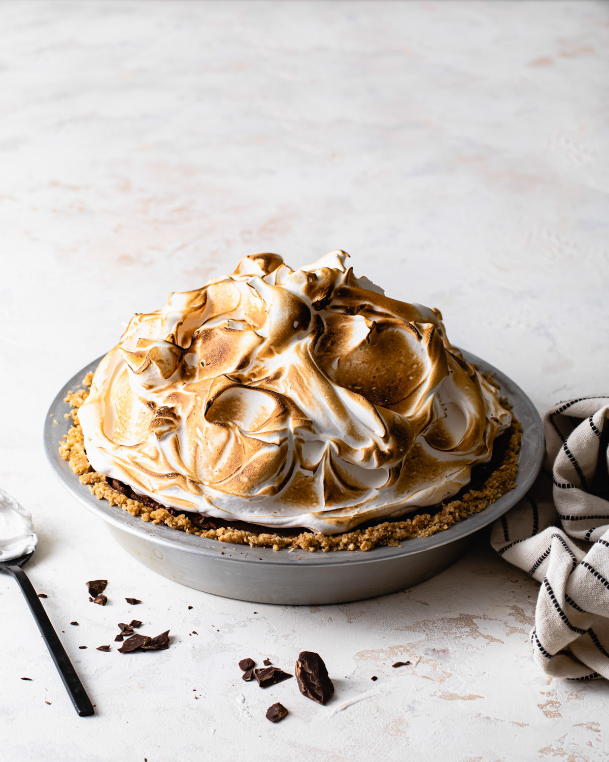 A peanut butter s'mores pie with toasted meringue topping in a pie tin