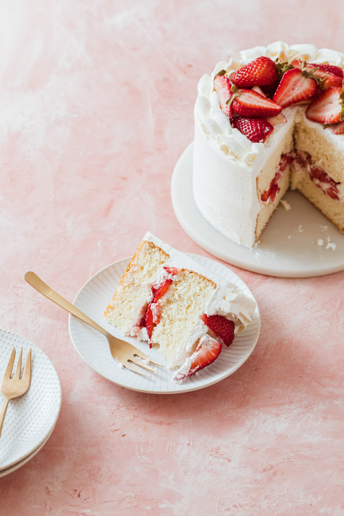 A slice of mii chiffon cake with sliced strawberries and whipped cream frosting