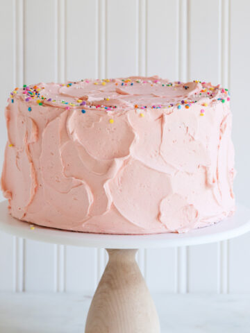A layer cake with pink Swiss meringue buttercream and sprinkels