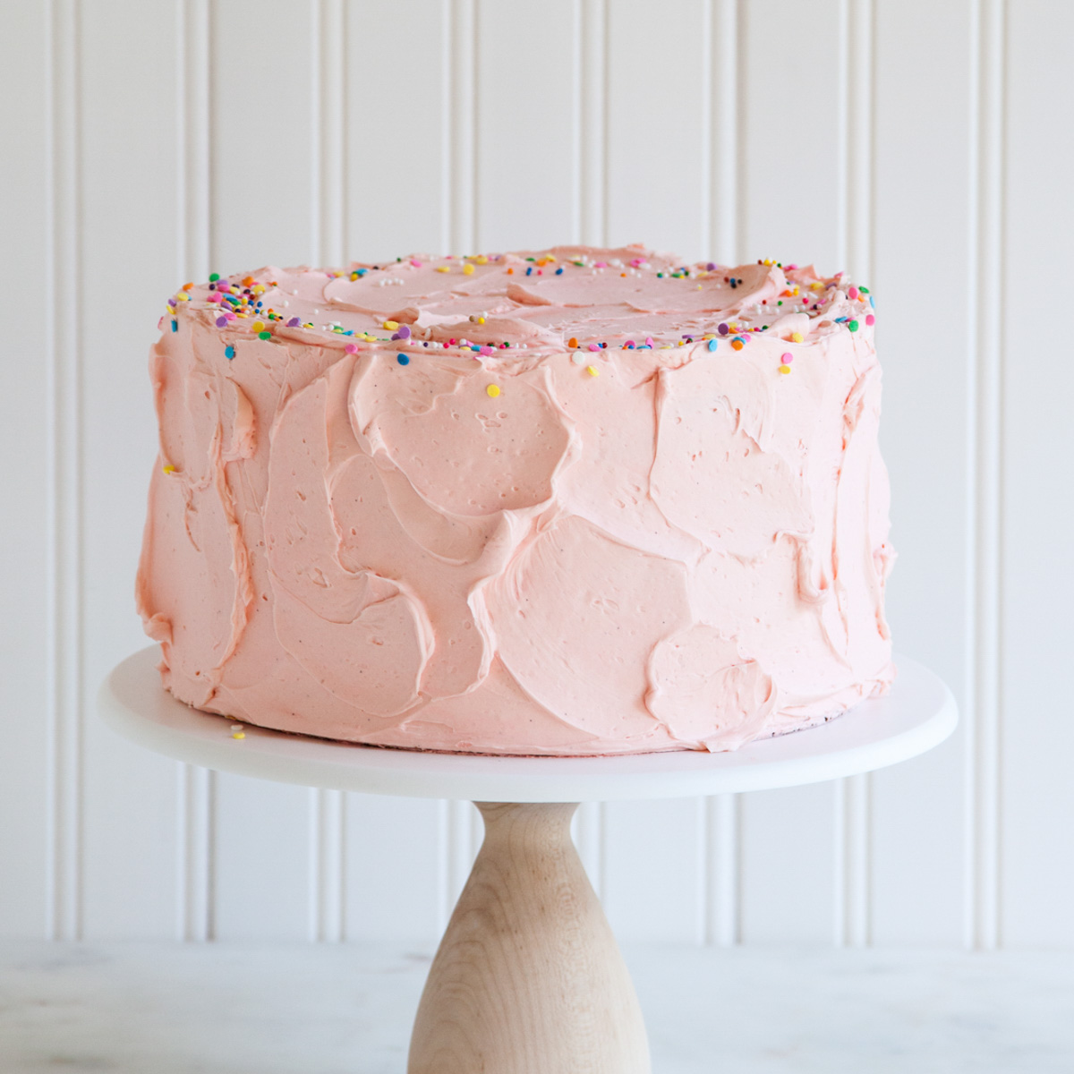 A layer cake with pink Swiss meringue buttercream and sprinkels