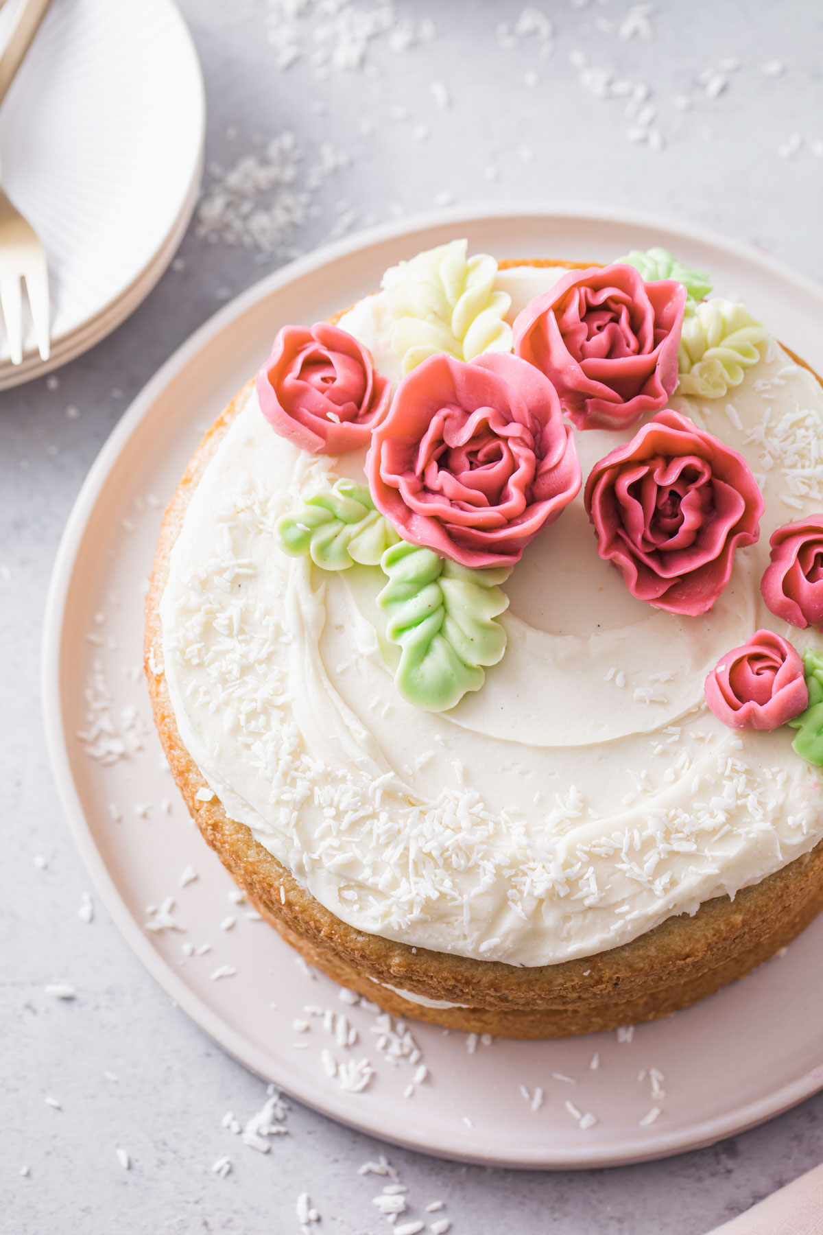 An overhead view of an almond layer cake with buttercream roses on top