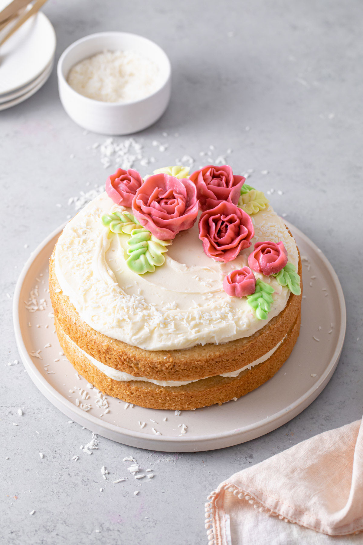 An almond layer cake with cream cheese frosting and pink buttercream rose on top