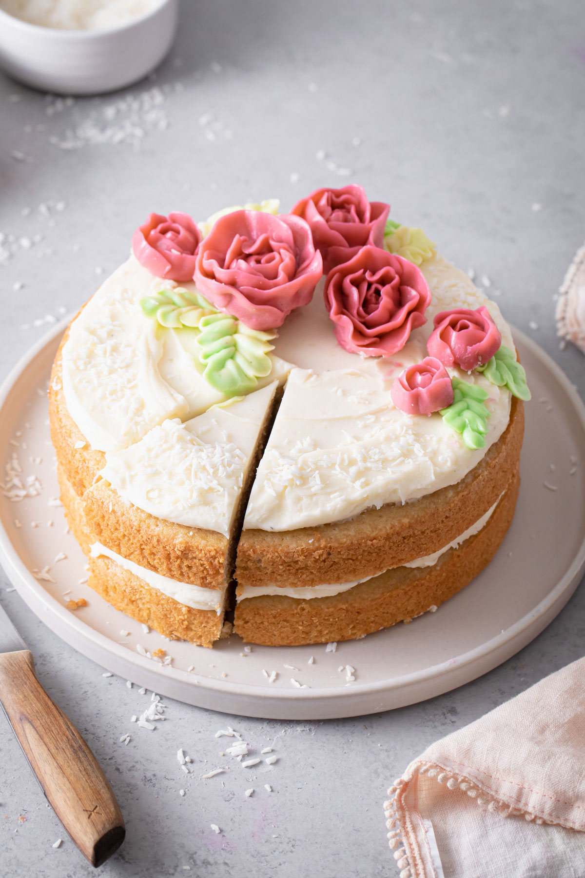 A two-layer almond cake with cream cheese frosting and pink buttercream roses on top