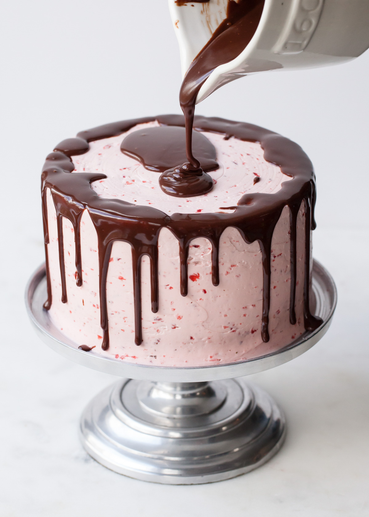 Pour glaze on a chocolate drip cake
