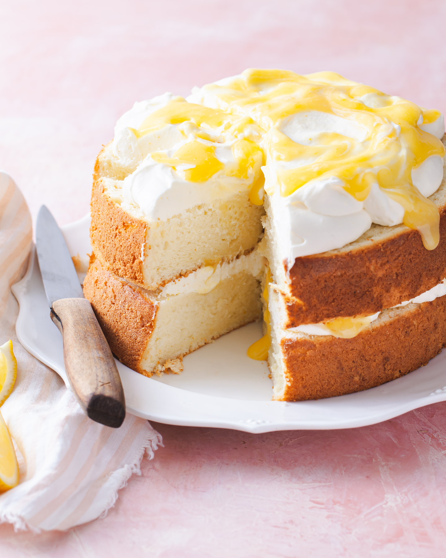 A two layer lemon chiffon cake with swirls of lemon curd on top that has been sliced