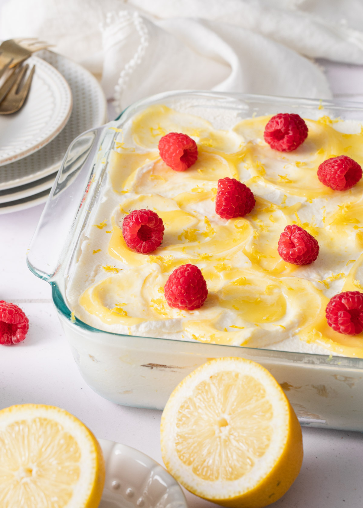 The top of an icebox cake with swirls of lemon curd and fresh raspberries on top.
