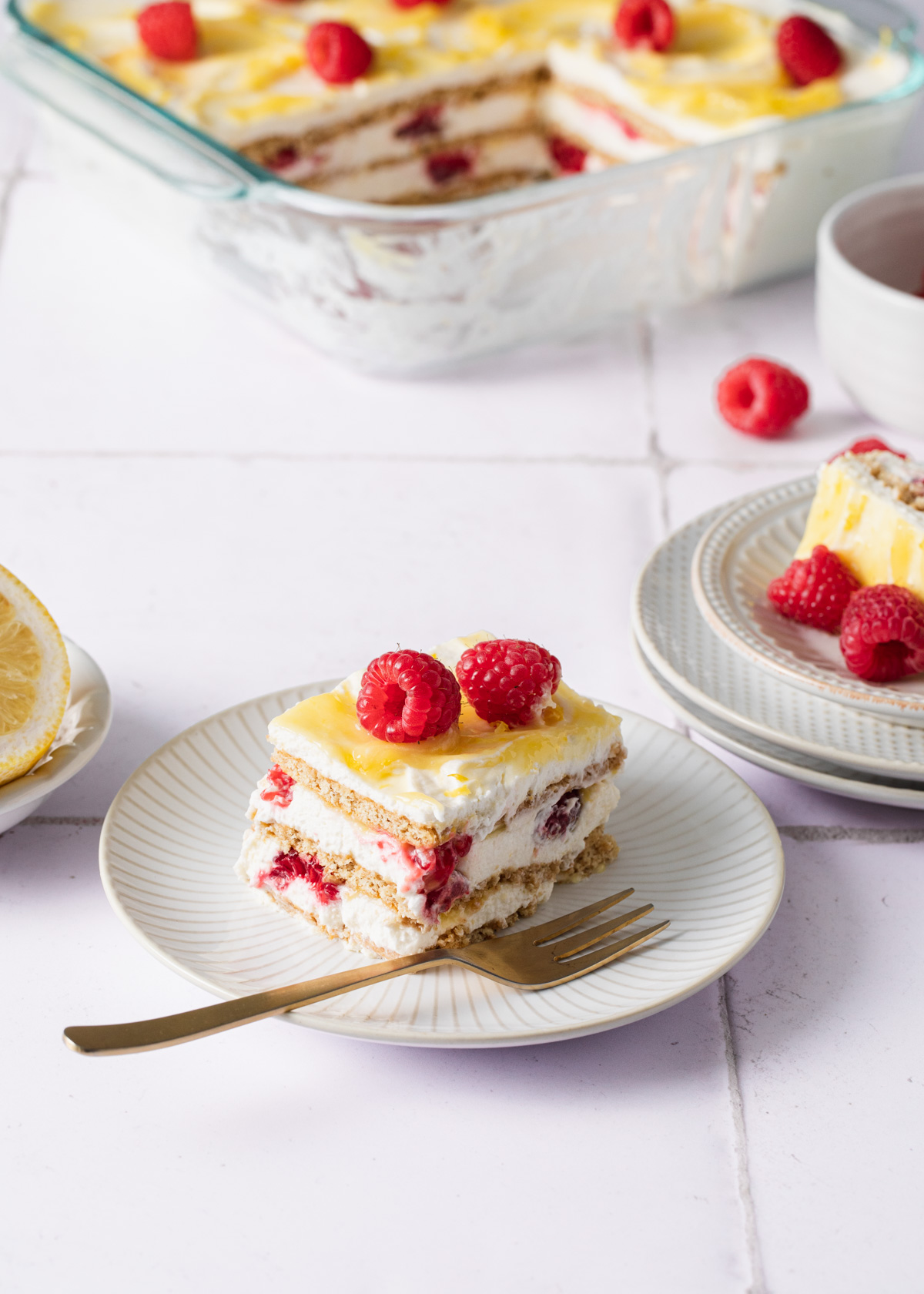 A slice of lemon icebox cake with fresh raspberries on a plate.