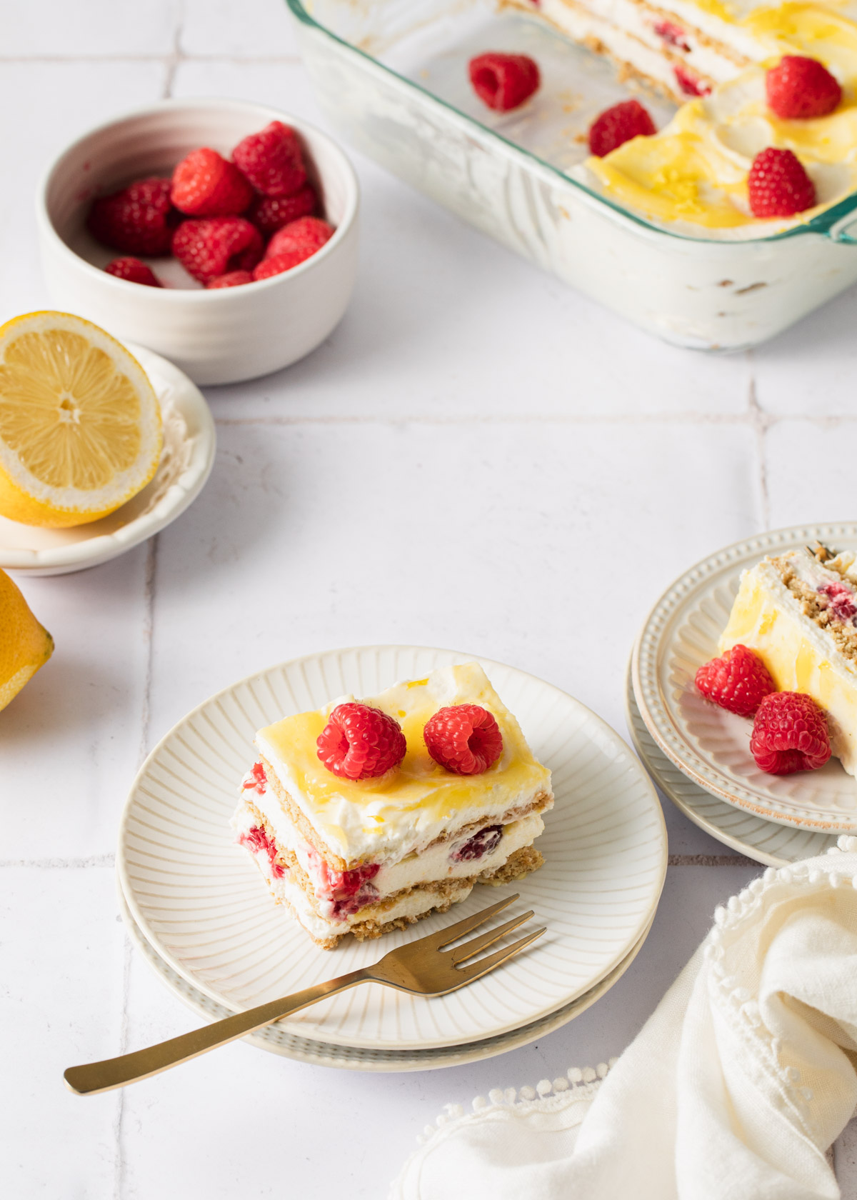 A lemon icebox cake with has been sliced and served with fresh raspberries on top