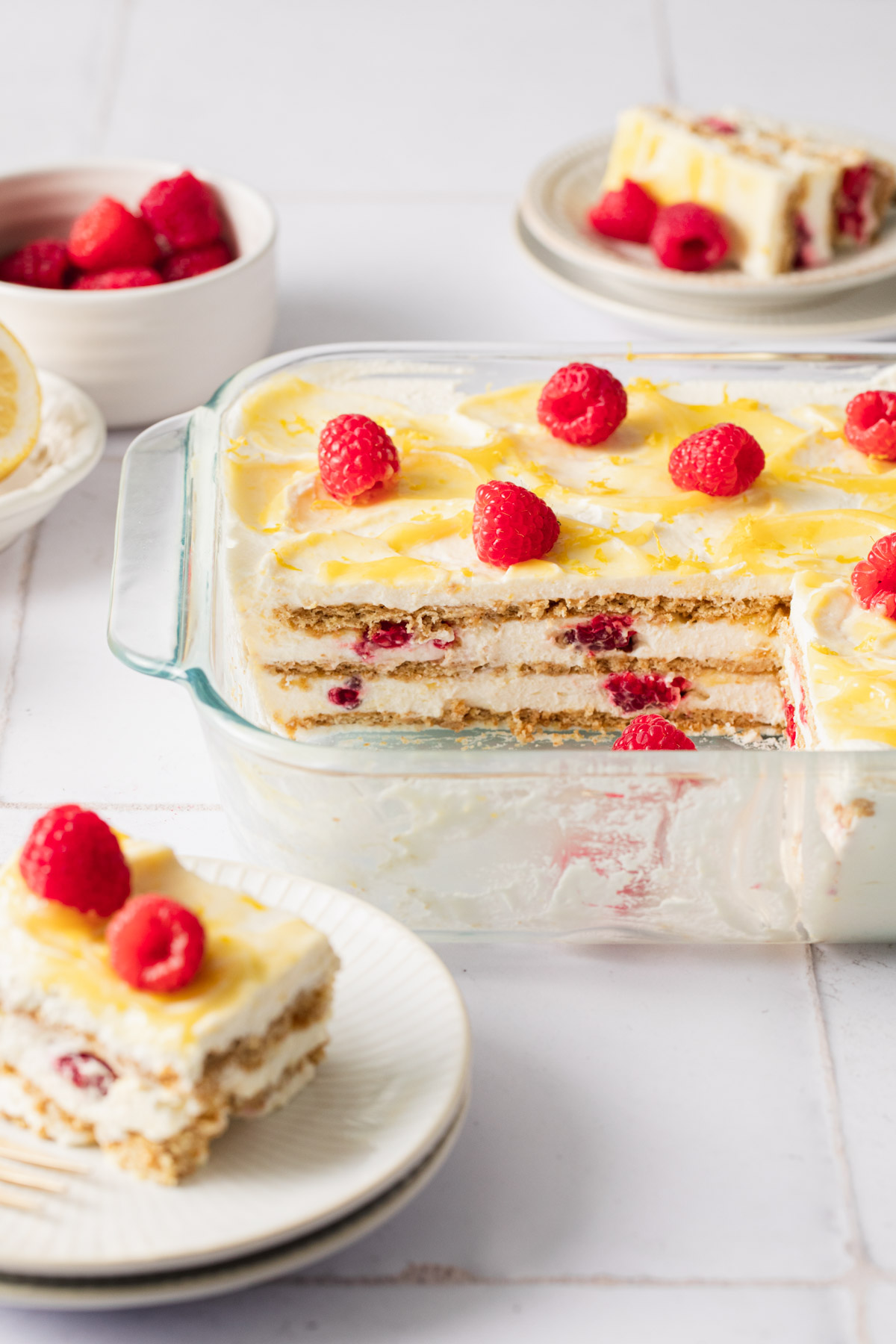 Lemon icebox cake layered with raspberries and graham crackers in a glass pan
