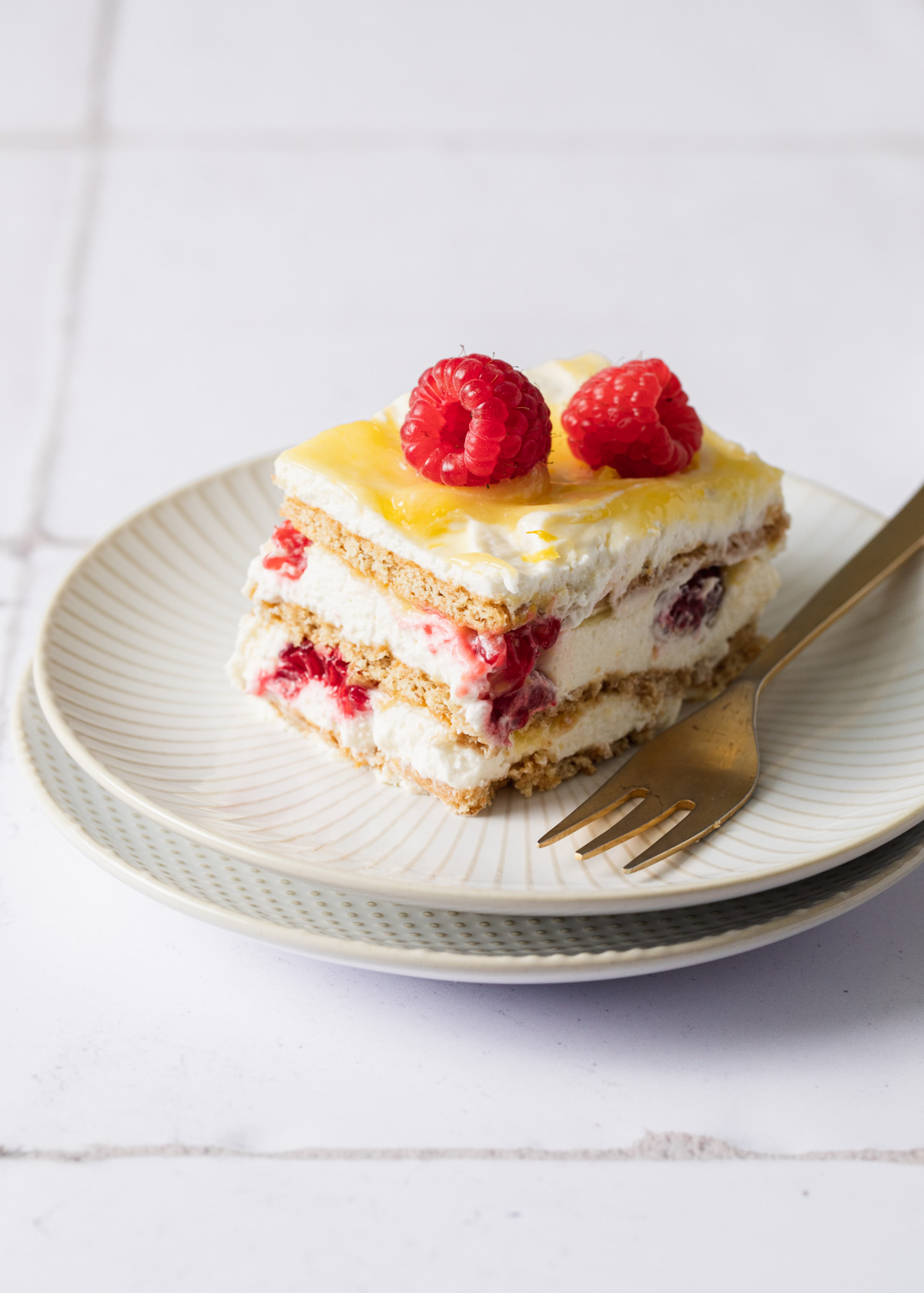 A slice of icebox cake with fresh raspberries and lemon curd on top