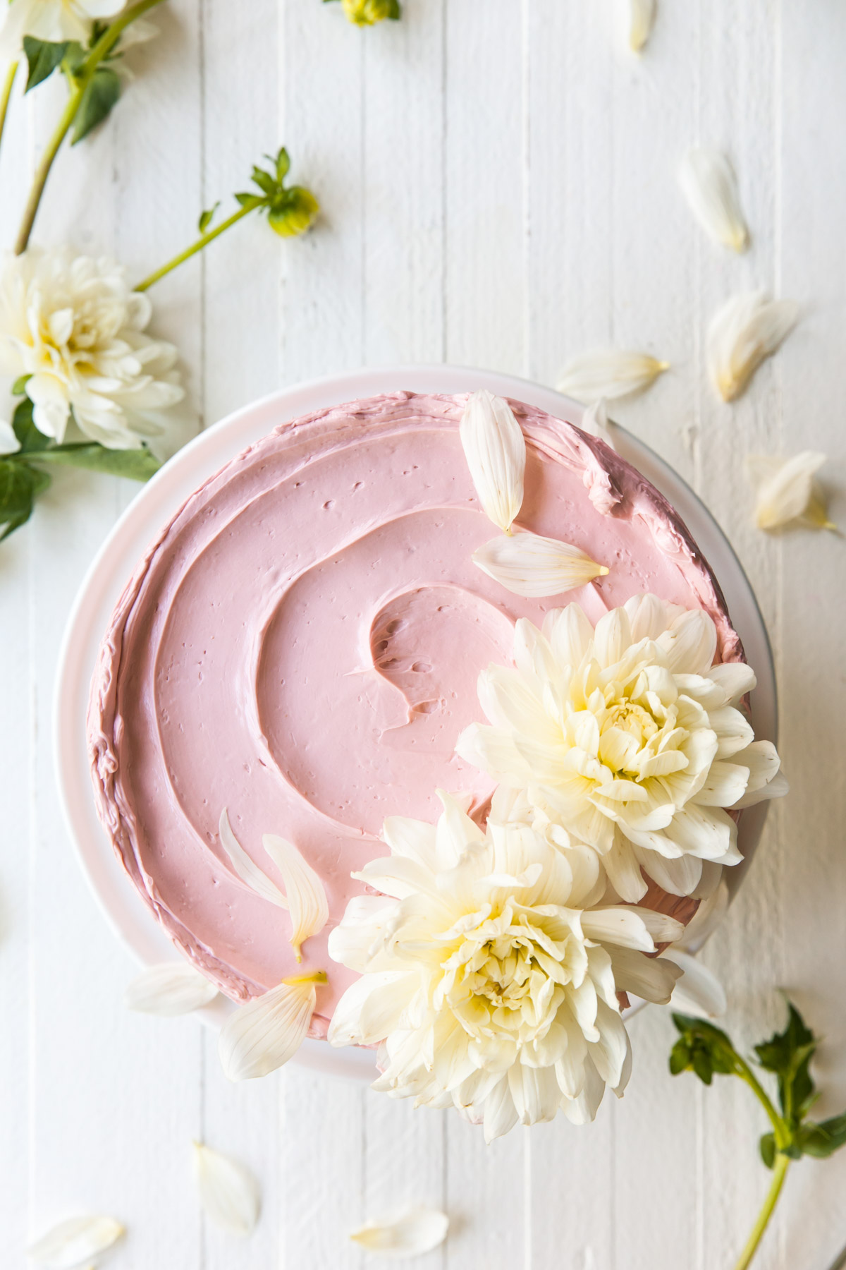 A pink buttercream cake with white flowers on top