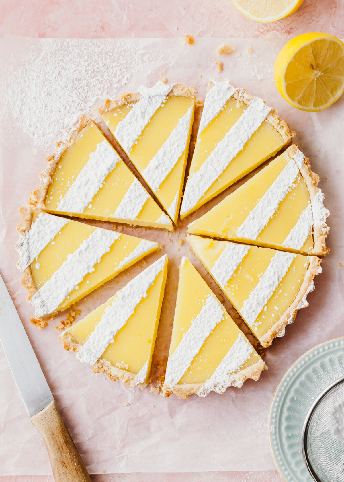 A lemon tart with confectioners' sugar dusted on top that has been sliced into wedges