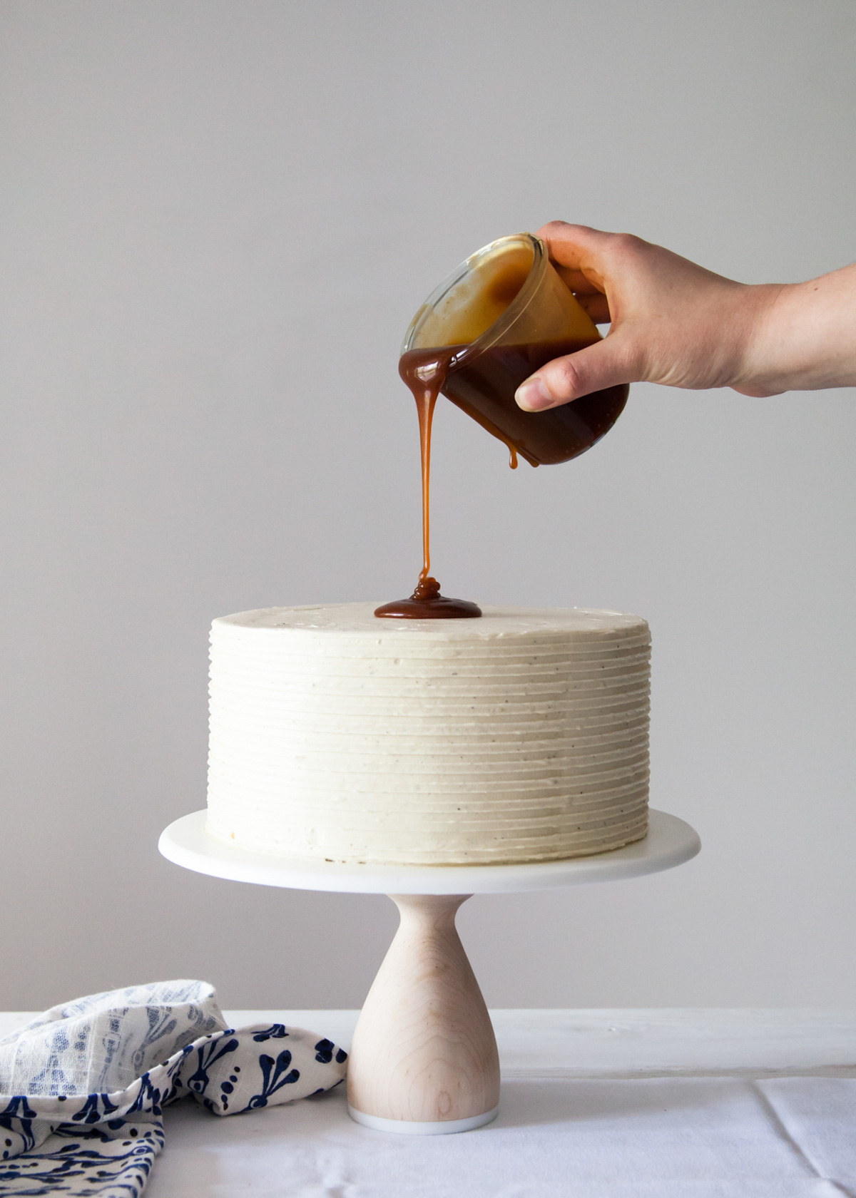Pouring caramel sauce on a frosted London Fog cake